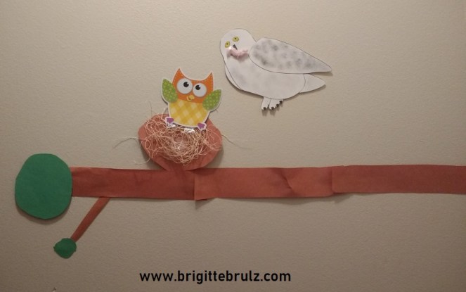 snowy owl and baby owl on limb